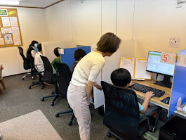 プログラミング教室で、先生が横について子どもの学習をフォローしている様子