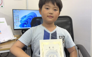 タイピングコンテストで銀賞を受賞し賞状を持つ小学3年生の生徒