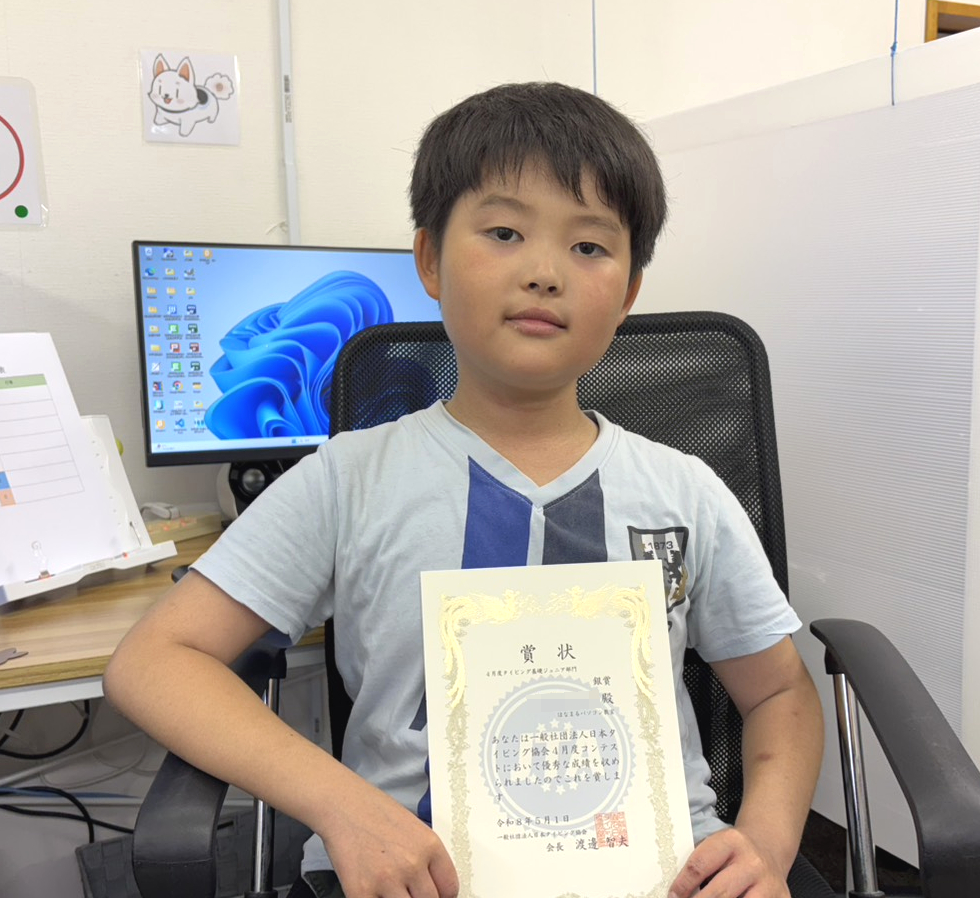 タイピングコンテストで銀賞を受賞し賞状を持つ小学3年生の生徒